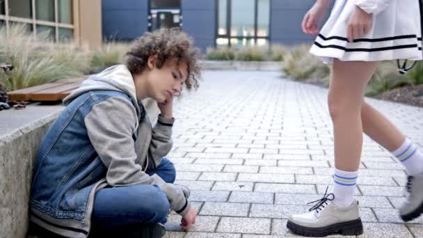 高校生の悲しい男が校庭の歩道に座り 彼女を待っている 女の子が来て 彼らは一緒に学校に行く 学校の友情 最初の愛 — ストック動画