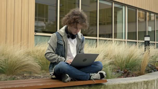 Chlápek Sedí Laptopem Lavičce Dvorku Vzdělávací Instituce Něčeho Nadšený Vyhrát — Stock video