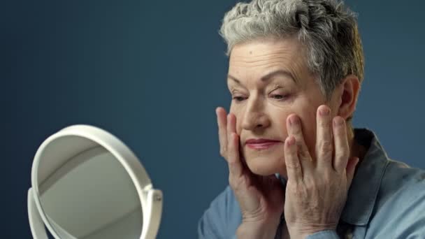 Elderly Gray Haired Woman Carefully Examines Her Reflection Mirror Lightly — Vídeos de Stock