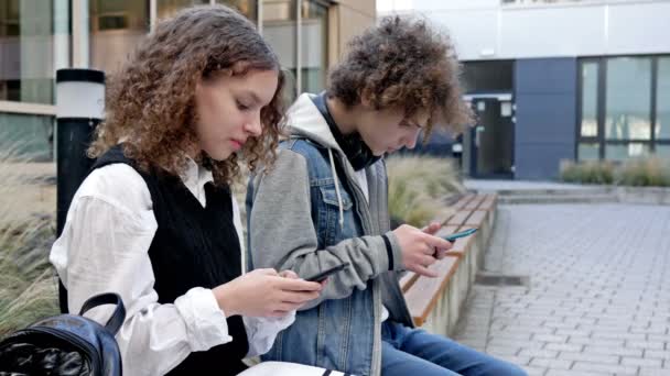 Dwóch Licealistów Chłopiec Dziewczynka Siedzą Ławce Szkolnym Podwórku Każdy Nastolatek — Wideo stockowe