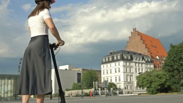 在一个美丽的城市广场上 戴着防护头盔的年轻女子骑着电动车 — 图库视频影像
