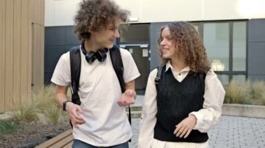 İki sevimli lise öğrencisi, bir erkek ve bir kız, üniversite bahçesinde dolaşıyorlar. Gençler canlı iletişim kuruyor. 4K.