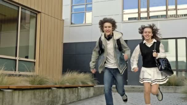 2人の学生 1人の少女と1人の男が教育機関の中庭を走っています 同級生たちはどこかで急いでいる 授業は遅い — ストック動画