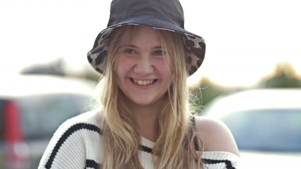 幸せなブロンドのティーンエイジャー14 16歳は街の通りの帽子に身を包んだ カメラを見てください 青年期だ — ストック動画
