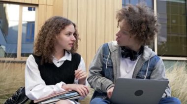 İki sevimli lise öğrencisi, bir erkek ve bir kız okul bahçesinde bir bankta oturuyorlar. Gençler bir şeyi tartışırken, dizüstü bilgisayara bakarken eğleniyorlar. 4K.
