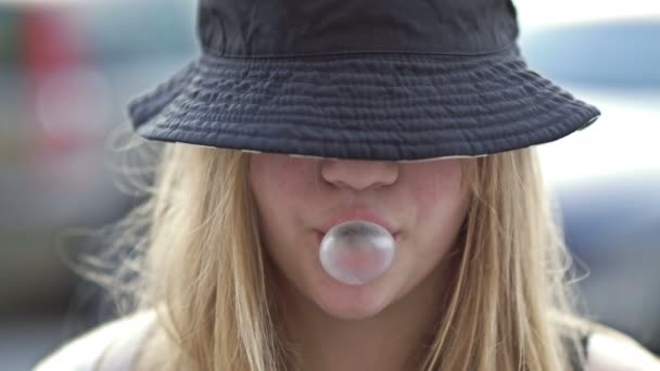 Teenage Girl Kloboukem Staženým Přes Oči Nafoukne Velkou Žvýkačkovou Bublinu — Stock video