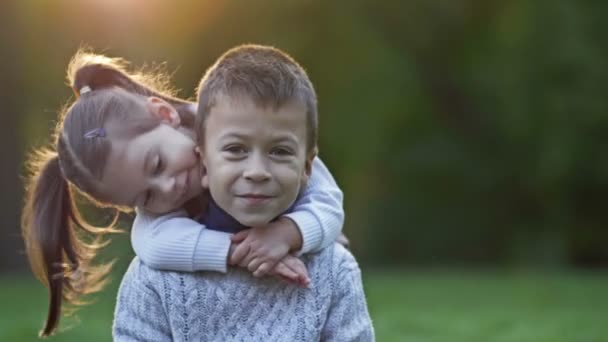 小さな女の子は優しく彼女の兄を抱擁し 遊び心のある彼の鼻に触れます 子供間の友情と優しさ — ストック動画