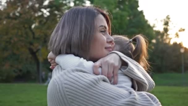 若い女性は優しく夏の公園で日没の散歩に彼女の若い娘を抱きしめます — ストック動画