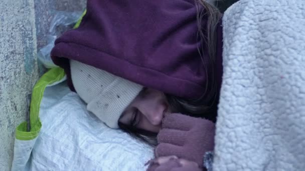 ホームレスの若い女性が路上で寝ている 寒地の上に寝そべっていると彼女は凍える — ストック動画