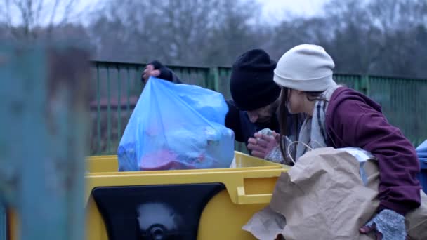 两个衣衫褴褛的无家可归的男人 一个男人和一个女人 正在一个垃圾桶里寻找一些东西 — 图库视频影像