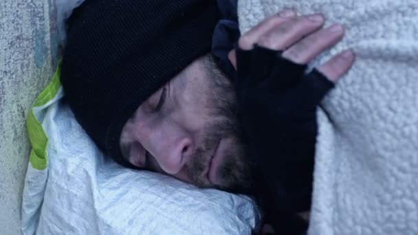 ホームレスの男が路上で寝ている 冷たい地面に寝そべっていると 彼は凍える — ストック動画