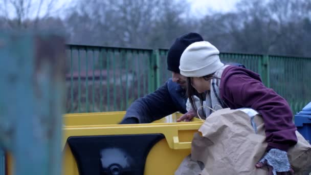 两个衣衫褴褛的无家可归的男人 一个男人和一个女人 正在一个垃圾桶里寻找一些东西 — 图库视频影像