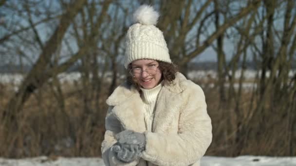 Vrolijk Tienermeisje Een Witte Gebreide Muts Bril Gooit Een Sneeuwbal — Stockvideo