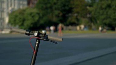 Tekme paylaşımı. Sırt çantalı bir adam elektrikli scooterı açmak ve kiralamak için telefonunu kullanıyor. HD.