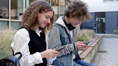 İki lise öğrencisi, bir oğlan ve bir kız, okul bahçesinde bir bankta oturuyorlar. Her gencin elinde kendi akıllı telefonu vardır. Gençlerin yeni teknolojik eğilimlere olan tutkusu. HD.
