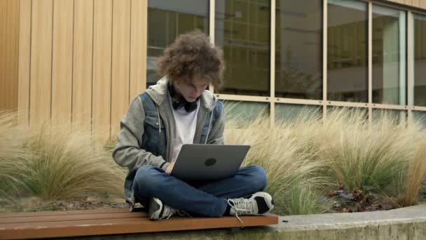 Eğitim Kurumunun Bahçesindeki Bankta Dizüstü Bilgisayarla Oturan Adam Bir Şeyden — Stok video