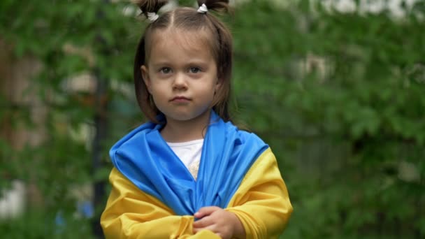 肩にウクライナの旗を持つ小さな笑顔の少女の肖像画 勝利への信仰の象徴として — ストック動画