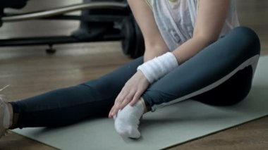 Young woman feels pain from an ankle injury while exercising at the gym. HD.