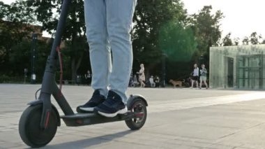 Güzel bir Avrupa şehrinin meydanında elektrikli scooterlı bir adam. 4K.