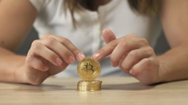 Womens hands are playing with a stack of bitcoins. HD.
