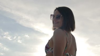 Young woman in a swimsuit near the lake hums and dances. HD.