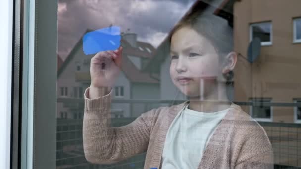 小さな女の子は窓にウクライナの旗を描きます — ストック動画