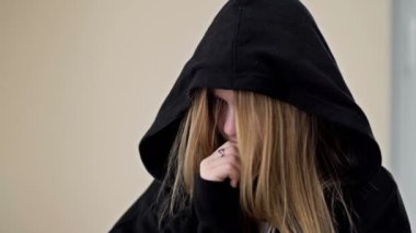 Kapüşonlu yüzünü kapüşonlu bir genç kız stresli bir durumda. 4K.
