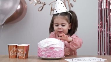 Little birthday girl tries the cream on the birthday cake. HD.