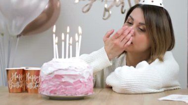 Sad birthday. Beautiful girl sits alone in front of a birthday cake and cries. 4K.