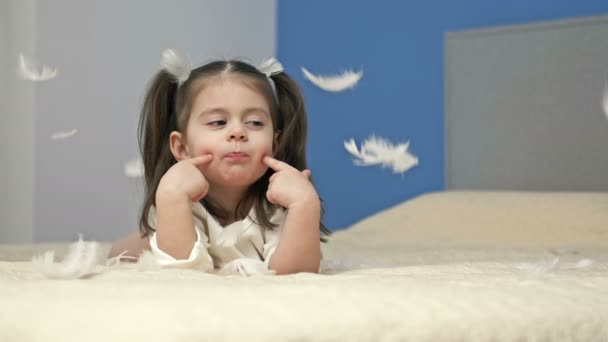 Ένα Τρίχρονο Κορίτσι Παίζει Φτερά Ξαπλωμένο Ένα Μεγάλο Κρεβάτι Στην — Αρχείο Βίντεο