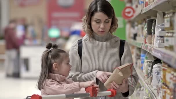 Mladá Matka Dítětem Polic Výrobky Supermarketu Žena Konzultuje Svou Dcerou — Stock video
