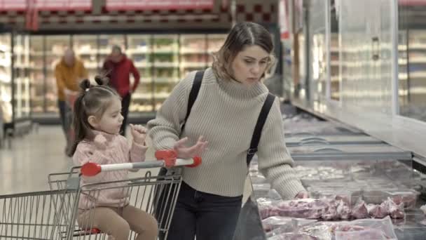 Mujer Joven Con Hija Pequeña Cerca Vitrinas Con Carne Supermercado — Vídeos de Stock