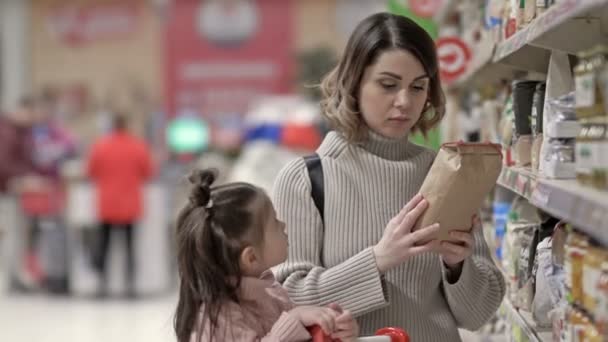 Młoda Matka Dzieckiem Pobliżu Półek Produktami Supermarkecie Kobieta Konsultuje Się — Wideo stockowe