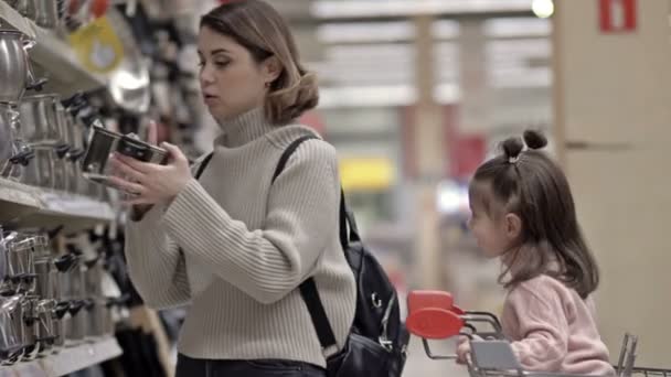Uma Jovem Com Filha Secção Louças Supermercado Bebê Senta Carrinho — Vídeo de Stock