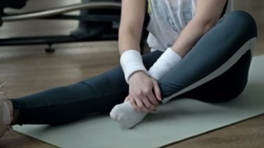Genç bir kadın spor salonunda egzersiz yaparken ayak bileğinden yaralandığı için acı çekiyor. 4K.
