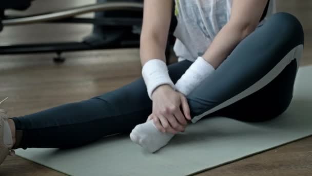 若い女は体育館で運動をしながら足首の怪我で痛みを感じる — ストック動画