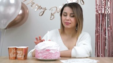 Beautiful young woman tries cream from a birthday cake. HD.