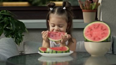 Küçük kız sulu olgun bir karpuzu zevkle yiyor. HD.