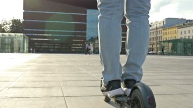 Güzel bir Avrupa şehrinin meydanında elektrikli scooterlı bir adam. HD.