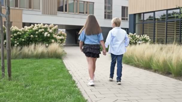 Bir Erkek Bir Kız Ilkokul Öğrencileri Okul Bahçesinde Ele Yürüyorlar — Stok video