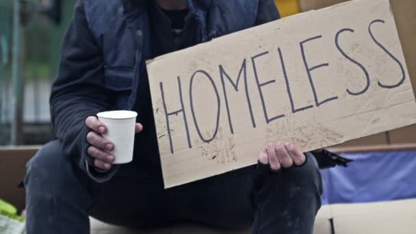 Žebrajícího Kalichu Sedí Rozcuchaný Muž Drží Ručně Psaný Plakát Homeless — Stock video