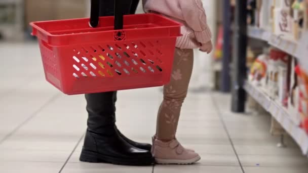 Beine Einer Frau Mit Einem Roten Einkaufskorb Neben Einem Regal — Stockvideo