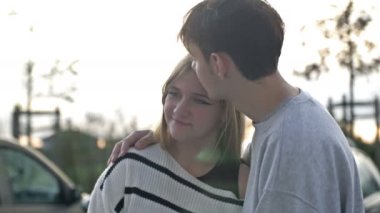 Birbirine aşık iki genç. Adam elini kız arkadaşının omzuna koydu ve ona sarıldı. 4K.
