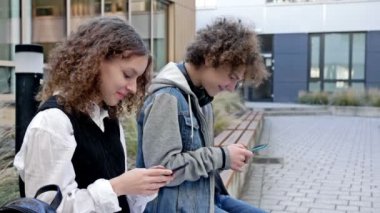 İki lise öğrencisi, bir oğlan ve bir kız, okul bahçesinde bir bankta oturuyorlar. Her gencin elinde kendi akıllı telefonu vardır. Gençlerin yeni teknolojik eğilimlere olan tutkusu. HD.