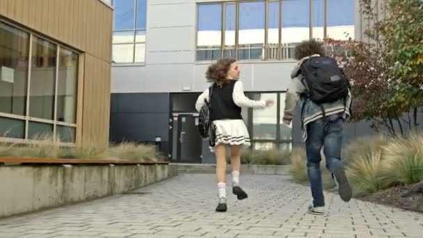 两个学生 一个是女生 一个是男生 在教育机构的院子里跑来跑去 同学们在某个地方赶时间 上课迟到了4K — 图库视频影像