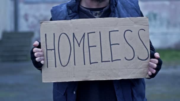 見苦しい男は手書きのホームレスのポスターを持っている — ストック動画