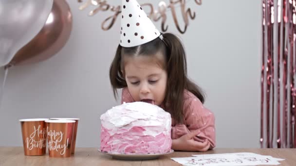 小さな誕生日の女の子は誕生日ケーキのクリームを舐める — ストック動画