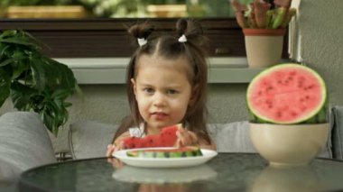 Küçük kız sulu olgun bir karpuzu zevkle yiyor. 4K.