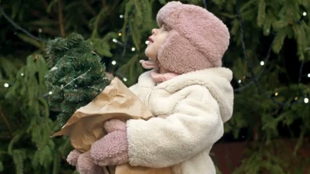 Річна Дівчинка Різдвяному Ринку Тримає Маленьку Ялинку Дитина Ловить Падаючі — стокове відео