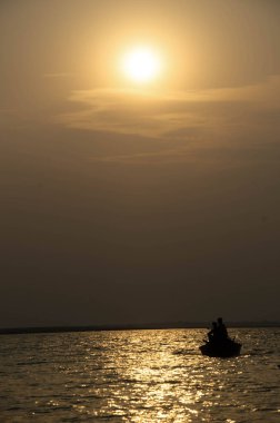 Gün batımında denizde yüzen bir geminin görüntüsü.